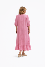 Cargar imagen en el visor de la galería, Vestido largo de lino rosa con botones frontales, mangas con volumen y volante en el bajo. Modelo de espaldas

