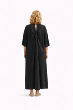 Cargar imagen en el visor de la galería, Vestido largo de algodón negro con diseño minimalista y espalda con abertura y detalle fruncido elegante con modelo de espaldas
